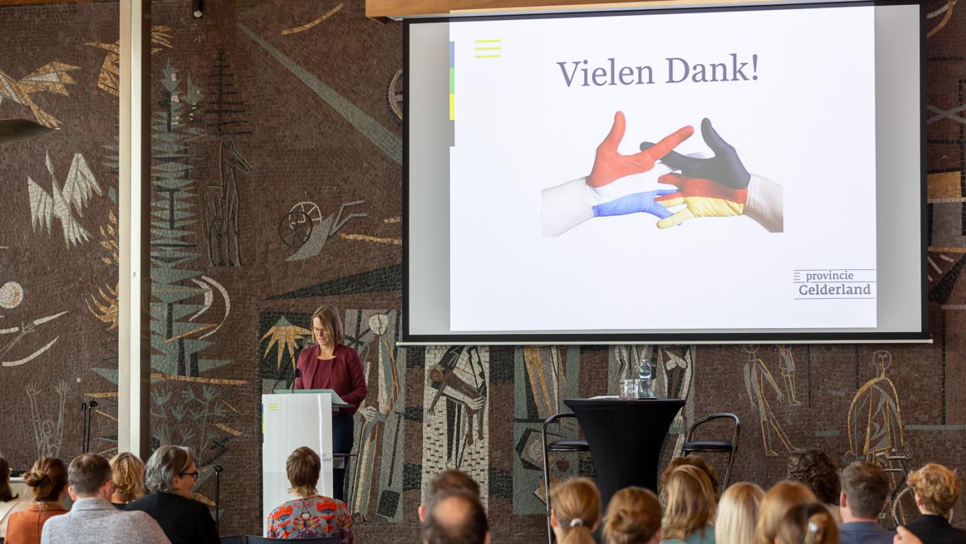 Leinwand zeigt ineinandergreifende Hände mit niederländischen und deutschen Flaggenfarben