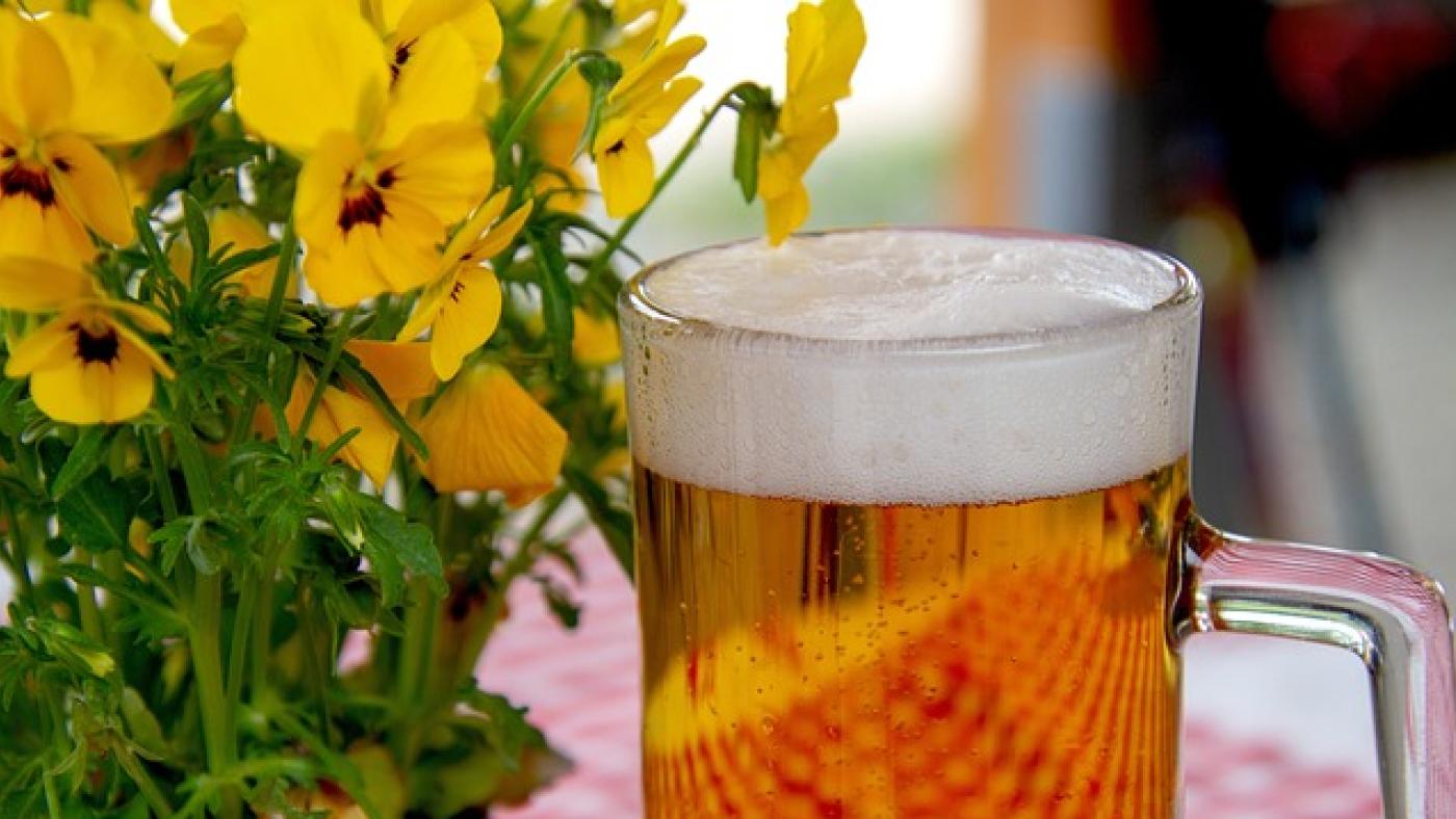 Bierglas steht auf Tisch neben einen Blumenstrauß
