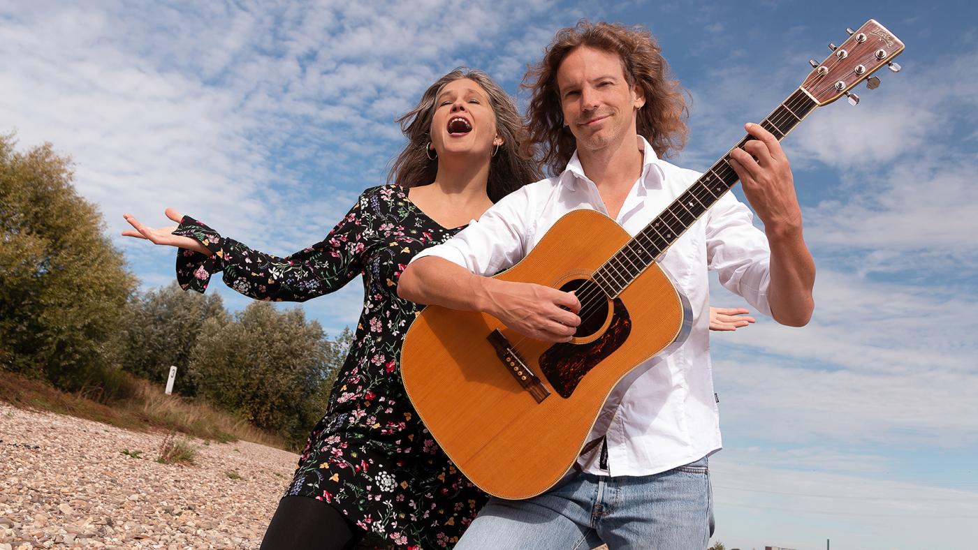 Sängerin und Gitarrist am Strand stehend