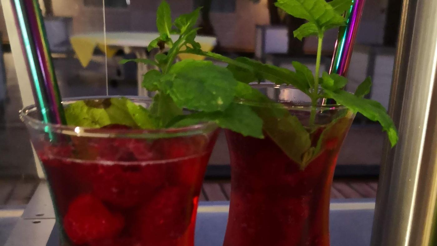 Zwei große Cocktailgläser mit grüner Deko stehen auf einer Theke