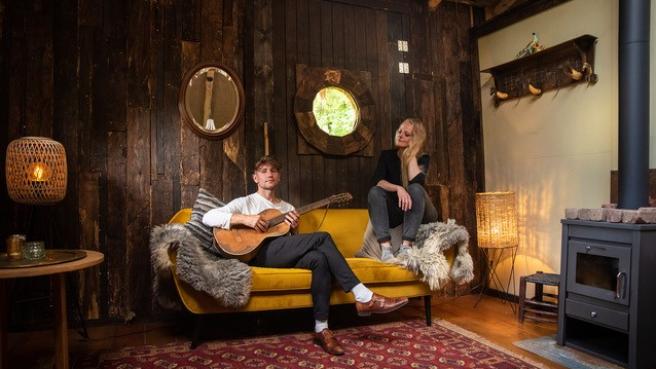 Ein Gitarrist und eine Sängerin sitzen auf einem Sofa