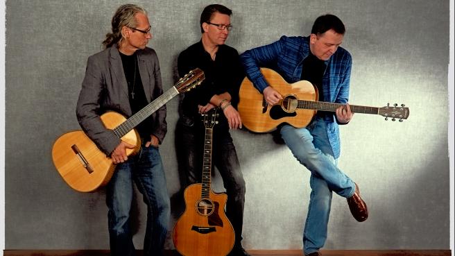 Drei Gitarristen an Wand gelehnt