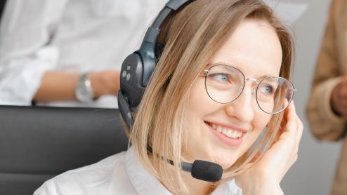 Eine Frau sitzt mit Headset vor ihrem Laptop